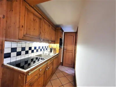 a kitchen with wooden cabinets and a sink at La Ginabelle – vue Mont Blanc avec piscine in Chamonix-Mont-Blanc