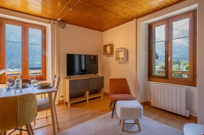 a living room with a television and a table and chairs at Rimaye Blanche - A bright and cozy 1 bed apartment in Chamonix-Mont-Blanc