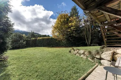 a backyard with a grassy yard with a wooden deck at Chalet Mont d'Arbois Ski et Golf in Megève