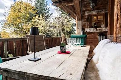 a wooden table on a deck with a bottle of champagne at Chalet Mont d'Arbois Ski et Golf in Megève