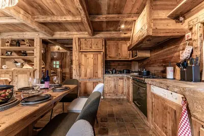 a kitchen with wooden cabinets and a table with chairs at Chalet Mont d'Arbois Ski et Golf in Megève