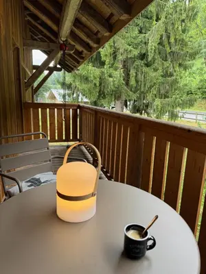 a table on a porch with a cup of coffee at Chalet La Foge - Samoens x 14, skis aux pieds in Morillon