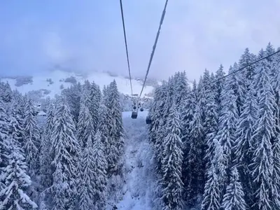 a ski lift in the middle of a snow covered forest at Appartement à Megève skis aux pieds - La CABOCHE in Le Planellet