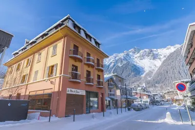 a building on a street with mountains in the background at Appartement De l'Aiguille Du Midi - Happy Rentals in Chamonix-Mont-Blanc