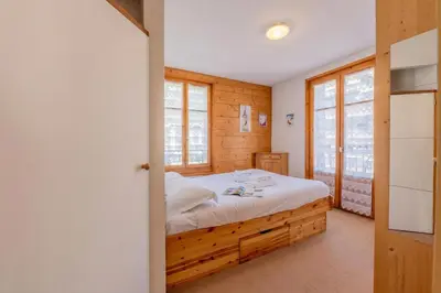 a bedroom with a bed in a room with windows at Appartement De l'Aiguille Du Midi - Happy Rentals in Chamonix-Mont-Blanc