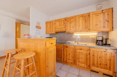 a kitchen with wooden cabinets and a counter with stools at Appartement De l'Aiguille Du Midi - Happy Rentals in Chamonix-Mont-Blanc