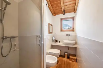 a bathroom with a sink and a toilet and two windows at Spacious loft on pedestrian street with views in Chamonix-Mont-Blanc