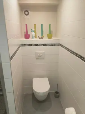a bathroom with a toilet and a shelf with vases at Beau studio dans la vallée de CHAMONIX in Les Houches