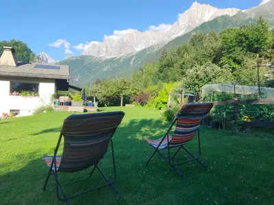 two chairs sitting in a yard with mountains in the background at Beau studio dans la vallée de CHAMONIX in Les Houches