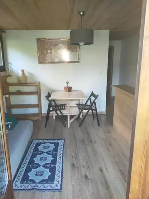a living room with a table and chairs in a room at Beau studio dans la vallée de CHAMONIX in Les Houches
