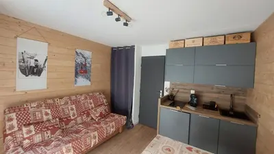 a living room with a couch and a kitchen at Studio cosy au pied des remontées,wifi,smart TV,parking in Les Contamines-Montjoie