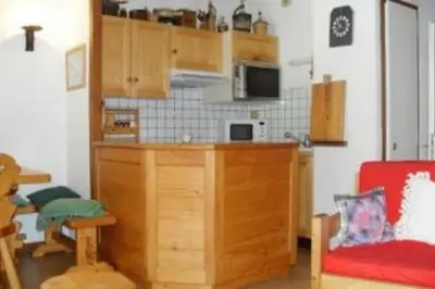 a kitchen with wooden cabinets and a red chair at Les Appartements Diochon in Le Baplieu