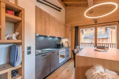 a kitchen with wooden cabinets and a table in a room at Appartement du Meu - Welkeys in Megève