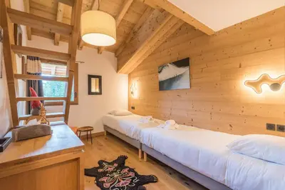two beds in a room with wooden walls at Appartement du Meu - Welkeys in Megève