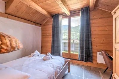 a bedroom with two beds and a large window at Appartement du Rosay - Welkeys in Saint-Gervais-les-Bains