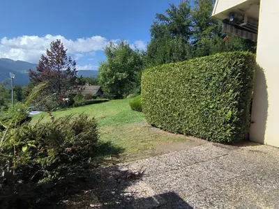 a hedge in front of a house with a yard at Appartement T3 familial rénové à Samoëns, animaux acceptés - FR-1-624-161 in Samoëns