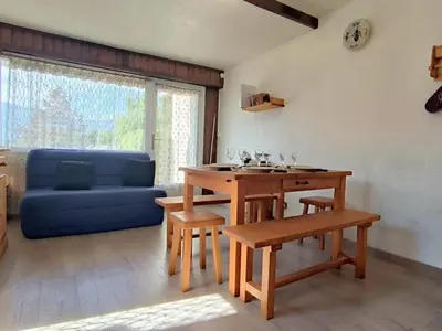 a living room with a table and a blue couch at Appartement T3 familial rénové à Samoëns, animaux acceptés - FR-1-624-161 in Samoëns