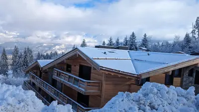 a log cabin with a snow covered roof at Appartement ludothèque familial neuf à Combloux in Combloux