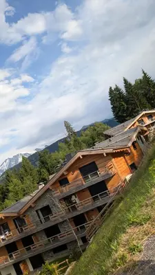 a building that is under construction on a hill at Appartement ludothèque familial neuf à Combloux in Combloux
