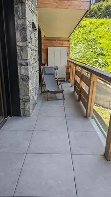 a patio with a chair and a table on a porch at Appartement ludothèque familial neuf à Combloux in Combloux