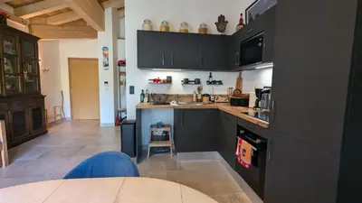 a kitchen with black cabinets and a sink at Appartement ludothèque familial neuf à Combloux in Combloux