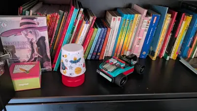 a shelf with books and a toy car and books at Appartement ludothèque familial neuf à Combloux in Combloux