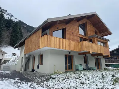 a house with a wooden facade in the snow at Chalet Cristal I in Les Contamines-Montjoie