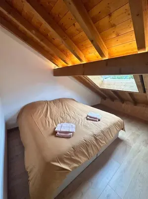 a bed in a attic with two towels on it at Le tilleul-cœur du village in Samoëns