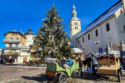 a group of people in a horse drawn carriage in front of a christmas tree at Exceptional view of village and mountain in Megève