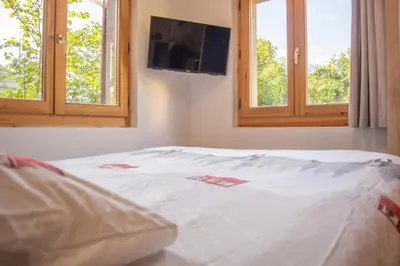 a bed in a bedroom with two windows at Studio Miloé secteur TMB in Saint-Gervais-les-Bains