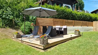 a patio with an umbrella and some chairs and flowers at Chalet OurSouris in Saint-Gervais-les-Bains