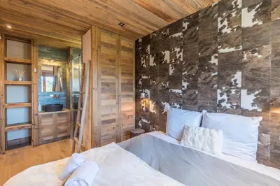 a bedroom with a bed and a wooden wall at Appartement de Charvin - Welkeys in Megève