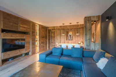 a living room with a blue couch and wooden walls at Appartement de Charvin - Welkeys in Megève