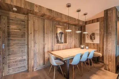 a dining room with wooden walls and a wooden table and chairs at Appartement de Charvin - Welkeys in Megève