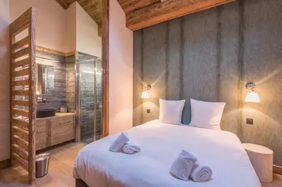 a bedroom with a large white bed and a bathroom at Appartement de Charvin - Welkeys in Megève