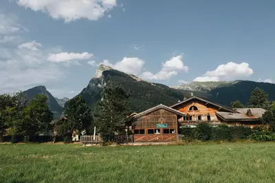 a house in a field with a mountain in the background at La table de Fifine - Montagne - Appartement 65m2 in Samoëns