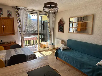 a living room with a blue couch and a table at Les Cîmes des Carroz in Les Carroz d'Araches