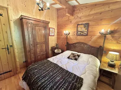 a bedroom with a bed and a wooden wall at Chalet 6-8 pers, 4 chambres, proche remontées, parking - FR-1-597-182 in Megève