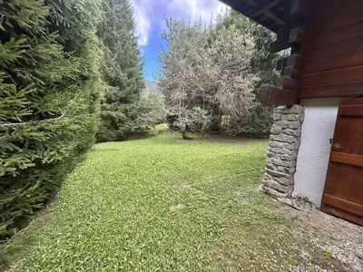 a yard with a stone wall next to a house at Chalet 6-8 pers, 4 chambres, proche remontées, parking - FR-1-597-182 in Megève