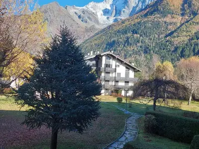 a house in the middle of a field with a tree at Studio confortable rénové en résidence verdoyante à Chamonix - FR-1-517-69 in Chamonix-Mont-Blanc
