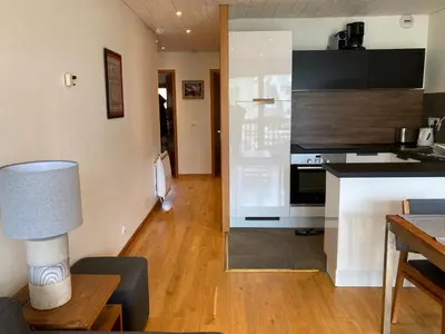 a kitchen with a white refrigerator and a kitchen table at Evasion Sérénité à Chamonix Mont-Blanc in Chamonix-Mont-Blanc
