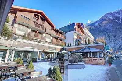 a hotel with tables and chairs in a courtyard at Evasion Sérénité à Chamonix Mont-Blanc in Chamonix-Mont-Blanc