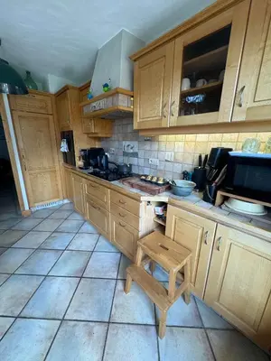 a kitchen with wooden cabinets and a wooden stool at Chalet les vergers in Sallanches