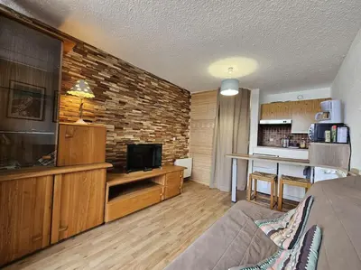 a living room with a couch and a tv and a kitchen at studio plein SUD été comme hiver in Les Carroz d'Araches