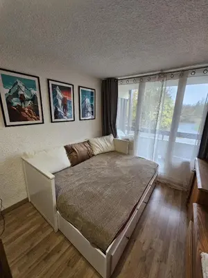 a bedroom with a large bed with pictures on the wall at studio plein SUD été comme hiver in Les Carroz d'Araches