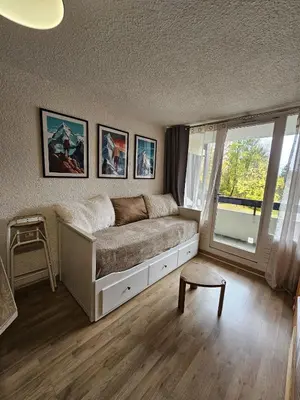 a bedroom with a bed and a large window at studio plein SUD été comme hiver in Les Carroz d'Araches