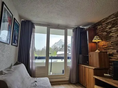 a bedroom with a large window with a view of a mountain at studio plein SUD été comme hiver in Les Carroz d'Araches