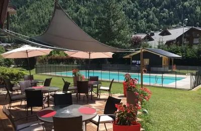 a patio with tables and chairs and a pool at Le Carolaz Studio cosy et familial pour 4 personnes in Les Contamines-Montjoie