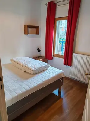 a bedroom with a bed with red curtains and a window at Appartement familial en résidence Saint Gervais les bains in Saint-Gervais-les-Bains