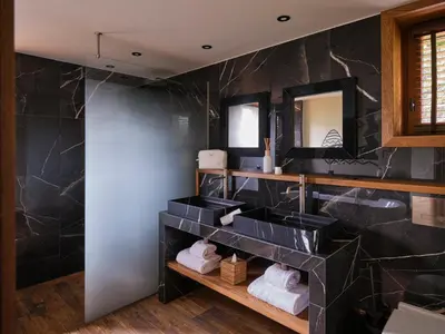 a bathroom with two sinks and black marble walls at Chalet Molitor, avec services, Collection Chalets des Fermes in Megève